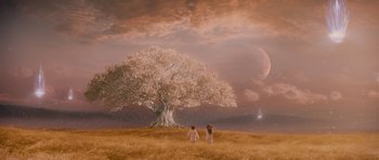 Movie still from “Knowing” (2009), directed by Alex Proyas – Two people standing in a field under a large tree; Extreme Wide shot, High angle