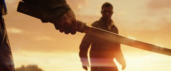 Movie still from “Kong: Skull Island” (2017), directed by Jordan Vogt-Roberts – A man holding a knife in front of another man; Extreme Close Up shot, Low angle