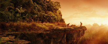 Movie still from “Kong: Skull Island” (2017), directed by Jordan Vogt-Roberts – An animal standing on top of a hill near a forest; Extreme Wide shot, Low angle
