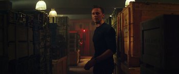 Movie still from “Kong: Skull Island” (2017), directed by Jordan Vogt-Roberts – A man standing in a dark room holding a gun; Medium shot, Over the shoulder angle