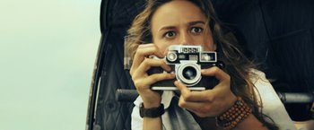 Movie still from “Kong: Skull Island” (2017), directed by Jordan Vogt-Roberts – A woman taking a picture with a camera; Close Up shot, Low angle