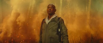 Movie still from “Kong: Skull Island” (2017), directed by Jordan Vogt-Roberts – A man with a gun in his hand standing in front of fire; Medium shot, Low angle