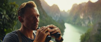 Movie still from “Kong: Skull Island” (2017), directed by Jordan Vogt-Roberts – A person holding a pair of binoculars; Close Up shot, Over the shoulder angle