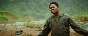 Movie still from “Kong: Skull Island” (2017), directed by Jordan Vogt-Roberts – A man standing in a field with a lake in the background; Close Up shot, Over the shoulder angle