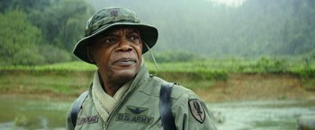 Movie still from “Kong: Skull Island” (2017), directed by Jordan Vogt-Roberts – An older man in a military uniform is looking at the camera; Close Up shot, Over the shoulder angle