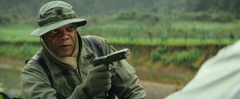 Movie still from “Kong: Skull Island” (2017), directed by Jordan Vogt-Roberts – A man holding a gun while standing on top of a hill; Close Up shot, Over the shoulder angle