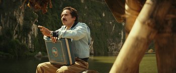 Movie still from “Kong: Skull Island” (2017), directed by Jordan Vogt-Roberts – A man sitting on the back of a boat holding a briefcase; Medium shot, Low angle