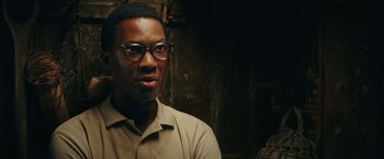 Movie still from “Kong: Skull Island” (2017), directed by Jordan Vogt-Roberts – A man wearing glasses and a tan shirt; Close Up shot, Over the shoulder angle