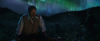 Movie still from “Kong: Skull Island” (2017), directed by Jordan Vogt-Roberts – An old man sitting in a field under a green sky; Medium shot, Over the shoulder angle