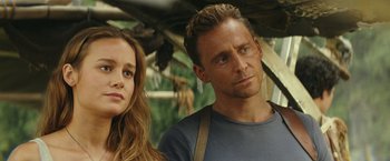 Movie still from “Kong: Skull Island” (2017), directed by Jordan Vogt-Roberts – A man and a woman standing next to each other; Close Up shot, Over the shoulder angle