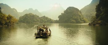 Movie still from “Kong: Skull Island” (2017), directed by Jordan Vogt-Roberts – A boat traveling down a river with mountains in the background; Extreme Wide shot, High angle