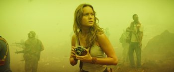 Movie still from “Kong: Skull Island” (2017), directed by Jordan Vogt-Roberts – A woman is holding a camera in a foggy area; Medium shot, Low angle