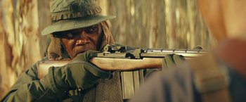 Movie still from “Kong: Skull Island” (2017), directed by Jordan Vogt-Roberts – A man with a hat is holding a rifle; Close Up shot, Over the shoulder angle