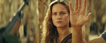 Movie still from “Kong: Skull Island” (2017), directed by Jordan Vogt-Roberts – A beautiful woman with long hair holding up a peace sign with one hand; Close Up shot, Over the shoulder angle