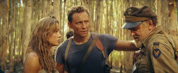 Movie still from “Kong: Skull Island” (2017), directed by Jordan Vogt-Roberts – A man and a woman are standing in the woods; Medium shot, Over the shoulder angle