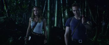 Movie still from “Kong: Skull Island” (2017), directed by Jordan Vogt-Roberts – A man and a woman standing next to each other in the woods; Medium shot, Over the shoulder angle