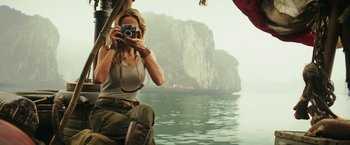 Movie still from “Kong: Skull Island” (2017), directed by Jordan Vogt-Roberts – A woman taking a picture of a body of water; Medium shot, Low angle