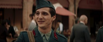 Movie still from “Lamborghini: The Man Behind the Legend” (2022), directed by Bobby Moresco – A man in a uniform is smiling for the camera; Close Up shot, Over the shoulder angle