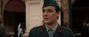 Movie still from “Lamborghini: The Man Behind the Legend” (2022), directed by Bobby Moresco – A young man in a military uniform is smiling for the camera; Close Up shot, Low angle