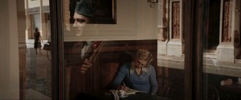 Movie still from “Lamborghini: The Man Behind the Legend” (2022), directed by Bobby Moresco – A woman sitting at a table writing on a notebook; Medium shot, Over the shoulder angle