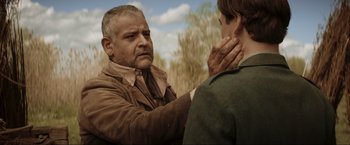 Movie still from “Lamborghini: The Man Behind the Legend” (2022), directed by Bobby Moresco – An older man is holding a younger man's neck; Close Up shot, Over the shoulder angle