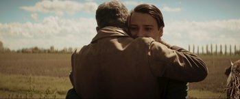 Movie still from “Lamborghini: The Man Behind the Legend” (2022), directed by Bobby Moresco – A man and a woman hugging in a field; Close Up shot, Over the shoulder angle