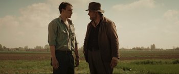 Movie still from “Lamborghini: The Man Behind the Legend” (2022), directed by Bobby Moresco – Two men standing next to each other on a field; Medium shot, Over the shoulder angle