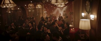 Movie still from “Lamborghini: The Man Behind the Legend” (2022), directed by Bobby Moresco – A group of people are dancing in a room; Extreme Wide shot, High angle