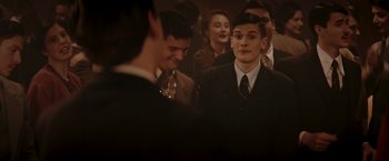 Movie still from “Lamborghini: The Man Behind the Legend” (2022), directed by Bobby Moresco – A group of people standing around each other in a room; Medium shot, Over the shoulder angle