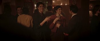 Movie still from “Lamborghini: The Man Behind the Legend” (2022), directed by Bobby Moresco – A group of people standing in a room holding drinks; Medium shot, Over the shoulder angle