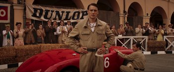 Movie still from “Lamborghini: The Man Behind the Legend” (2022), directed by Bobby Moresco – A man standing in front of a red race car; Medium shot, Low angle