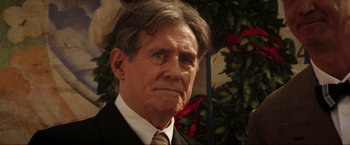 Movie still from “Lamborghini: The Man Behind the Legend” (2022), directed by Bobby Moresco – An older man wearing a suit and tie; Close Up shot, Over the shoulder angle