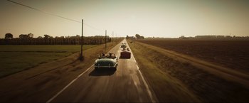 Movie still from “Lamborghini: The Man Behind the Legend” (2022), directed by Bobby Moresco – A group of cars driving down a road; Extreme Wide shot, High angle