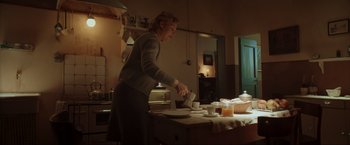 Movie still from “Lamborghini: The Man Behind the Legend” (2022), directed by Bobby Moresco – A woman pouring a cup of tea in a kitchen; Wide shot, Low angle