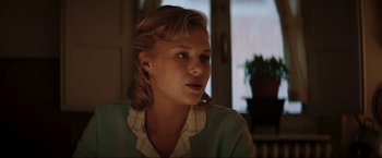 Movie still from “Lamborghini: The Man Behind the Legend” (2022), directed by Bobby Moresco – A young woman sitting in front of a window; Close Up shot, Over the shoulder angle