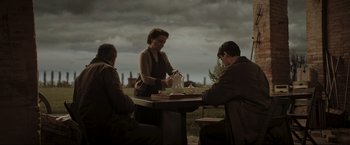 Movie still from “Lamborghini: The Man Behind the Legend” (2022), directed by Bobby Moresco – Three people sitting at a table with food; Wide shot, Over the shoulder angle