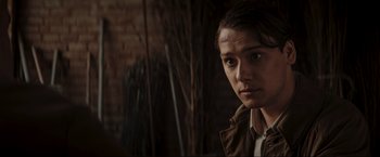 Movie still from “Lamborghini: The Man Behind the Legend” (2022), directed by Bobby Moresco – A young woman is looking at the camera while standing in front of a brick wall; Close Up shot, Over the shoulder angle