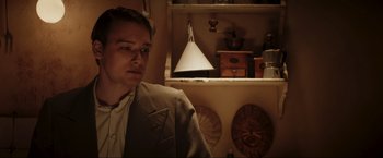 Movie still from “Lamborghini: The Man Behind the Legend” (2022), directed by Bobby Moresco – A man in a suit and tie in front of a shelf; Medium shot, Low angle