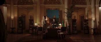 Movie still from “Lamborghini: The Man Behind the Legend” (2022), directed by Bobby Moresco – Two men in suits are standing at a desk; Wide shot, Low angle