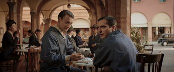 Movie still from “Lamborghini: The Man Behind the Legend” (2022), directed by Bobby Moresco – A group of men sitting at a table in a room; Medium shot, Over the shoulder angle