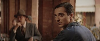 Movie still from “Lamborghini: The Man Behind the Legend” (2022), directed by Bobby Moresco – A person sitting in front of a brick wall; Close Up shot, Over the shoulder angle