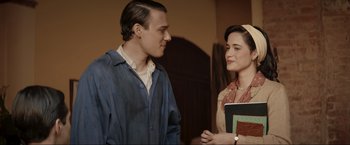 Movie still from “Lamborghini: The Man Behind the Legend” (2022), directed by Bobby Moresco – A man and a woman standing next to each other; Medium shot, Over the shoulder angle