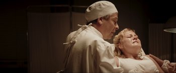 Movie still from “Lamborghini: The Man Behind the Legend” (2022), directed by Bobby Moresco – A man and a woman in a white lab coat; Medium shot, Low angle