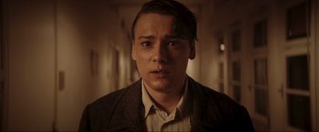 Movie still from “Lamborghini: The Man Behind the Legend” (2022), directed by Bobby Moresco – A young man in a brown jacket stares at the camera; Close Up shot, Low angle