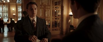 Movie still from “Lamborghini: The Man Behind the Legend” (2022), directed by Bobby Moresco – A man in a suit and tie sitting in front of a mirror; Medium shot, Over the shoulder angle