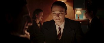 Movie still from “Lamborghini: The Man Behind the Legend” (2022), directed by Bobby Moresco – A man in a suit and tie next to another man in a suit and tie; Medium shot, Low angle