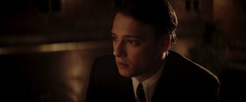 Movie still from “Lamborghini: The Man Behind the Legend” (2022), directed by Bobby Moresco – A man in a suit and tie sitting in a room; Close Up shot, Low angle