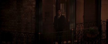 Movie still from “Lamborghini: The Man Behind the Legend” (2022), directed by Bobby Moresco – A man in a suit and tie standing in front of a building; Wide shot, Low angle