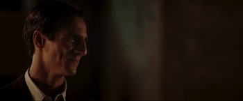 Movie still from “Lamborghini: The Man Behind the Legend” (2022), directed by Bobby Moresco – A person's face in a dark room; Close Up shot, Over the shoulder angle