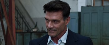 Movie still from “Lamborghini: The Man Behind the Legend” (2022), directed by Bobby Moresco – A person wearing a suit and tie; Close Up shot, Over the shoulder angle